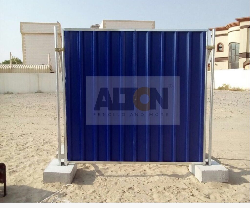 Large blue shipping container used as fencing on a concrete surface with buildings in the background.