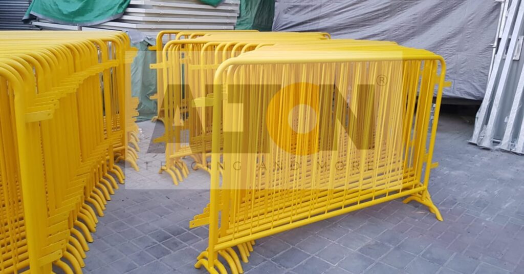 A stack of yellow metal barriers, often used for crowd control or to cordon off areas for safety or security purposes, interlocked and stored in an organized manner.