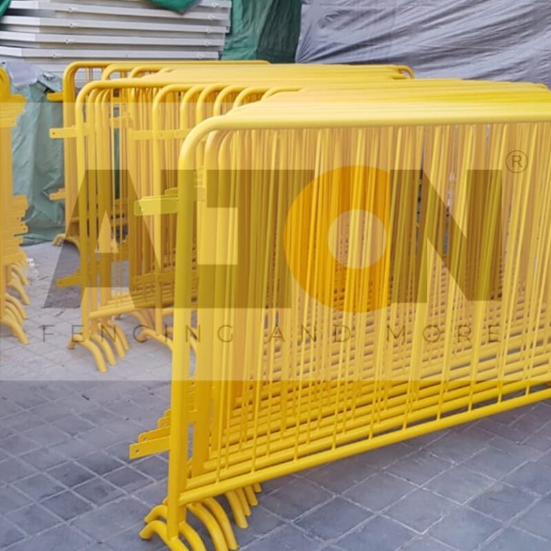 A stack of yellow metal barriers, often used for crowd control or to cordon off areas for safety or security purposes, interlocked and stored in an organized manner.