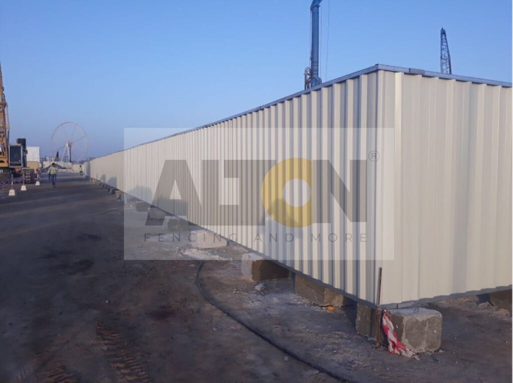 White container on a construction site with cranes in the background under clear skies.