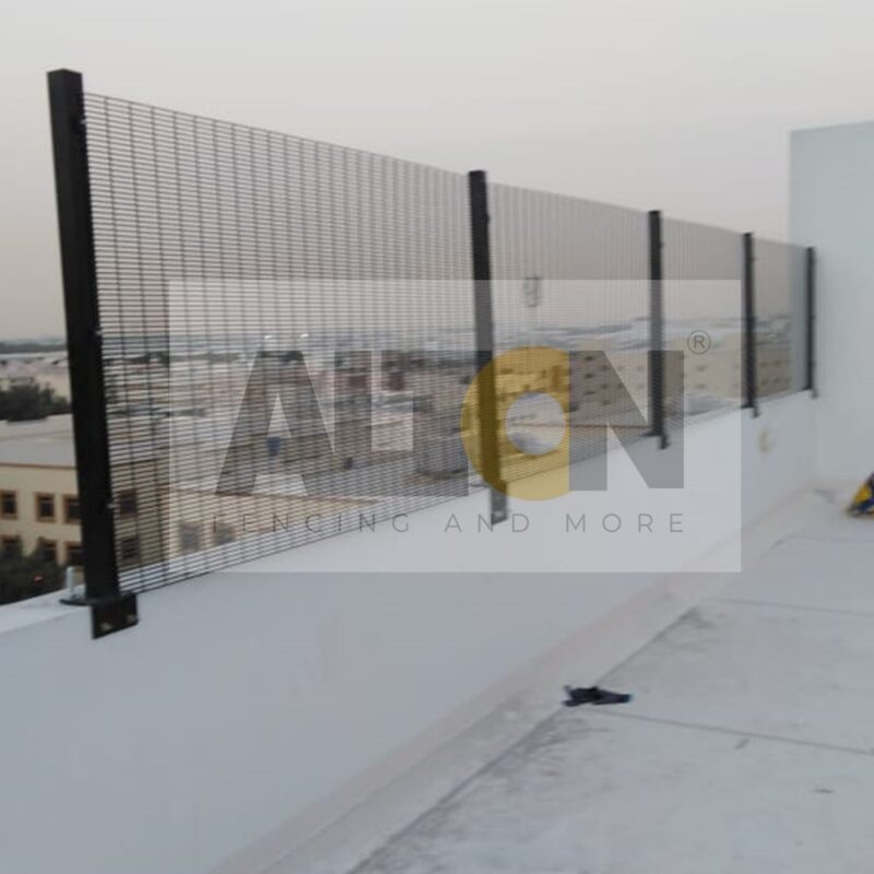 Pair of closed metal gates with a mesh pattern, leading to an industrial or commercial area.