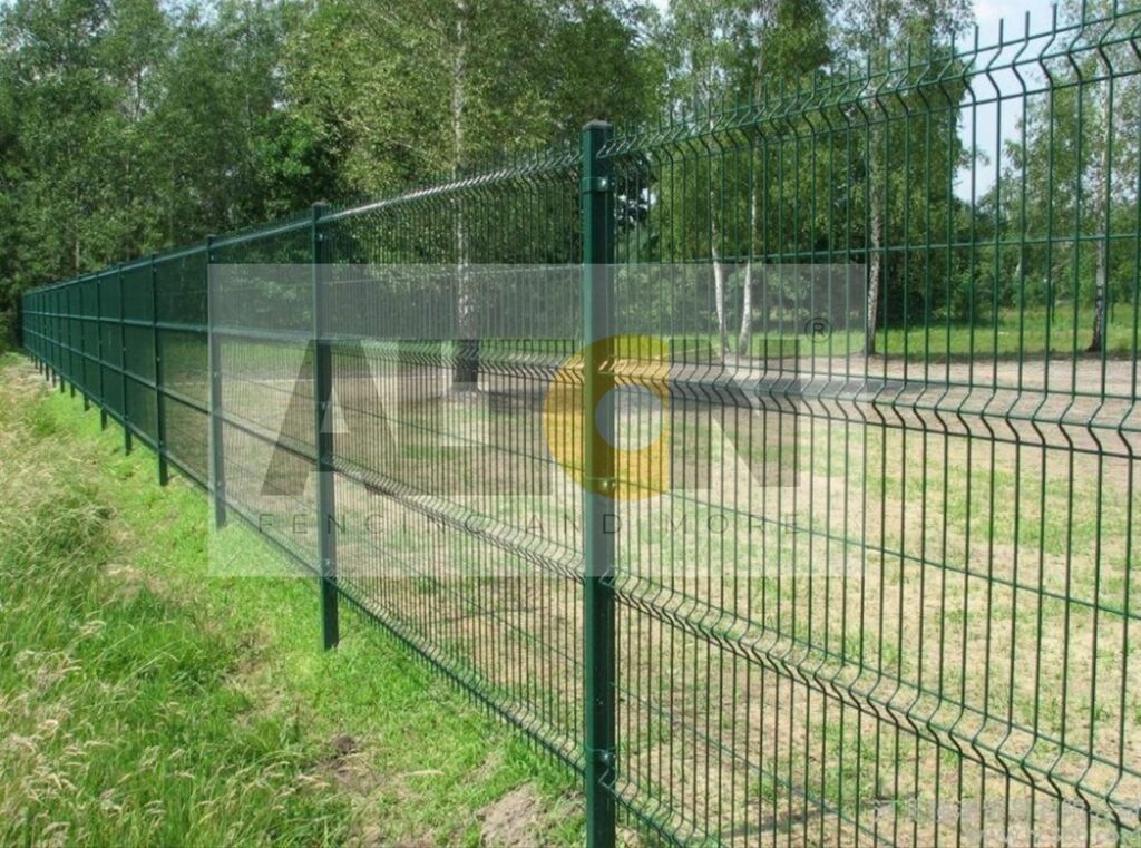 This image shows a construction site with large grey concrete blocks supporting a tall white metal fence. The fence features the branding “HIGH & MORE” with a stylized letter ‘H’ inside a yellow circle. This type of fencing is used for construction site security and branding.