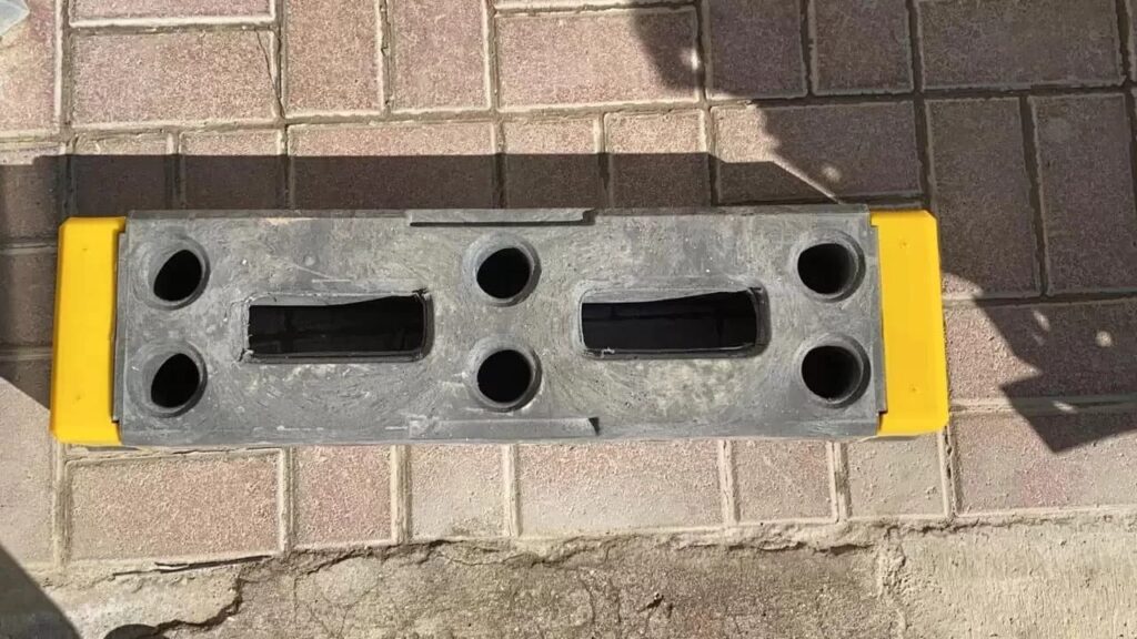 Yellow and gray plastic barricade on brick pavement, used for traffic control.