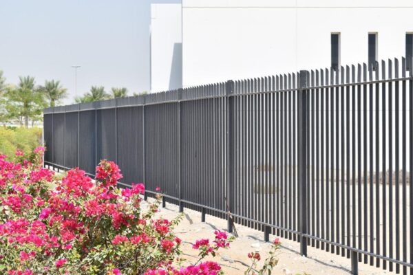 This black metal fence by Alton Fence stands in front of a white building.